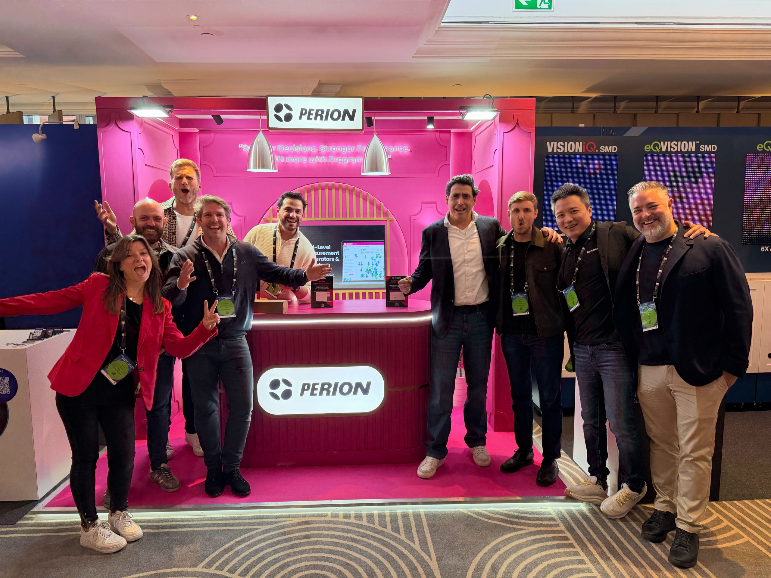 Team posing enthusiastically at a bright pink Perion trade show booth.