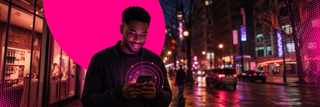Man using a smartphone while walking through a city at night.